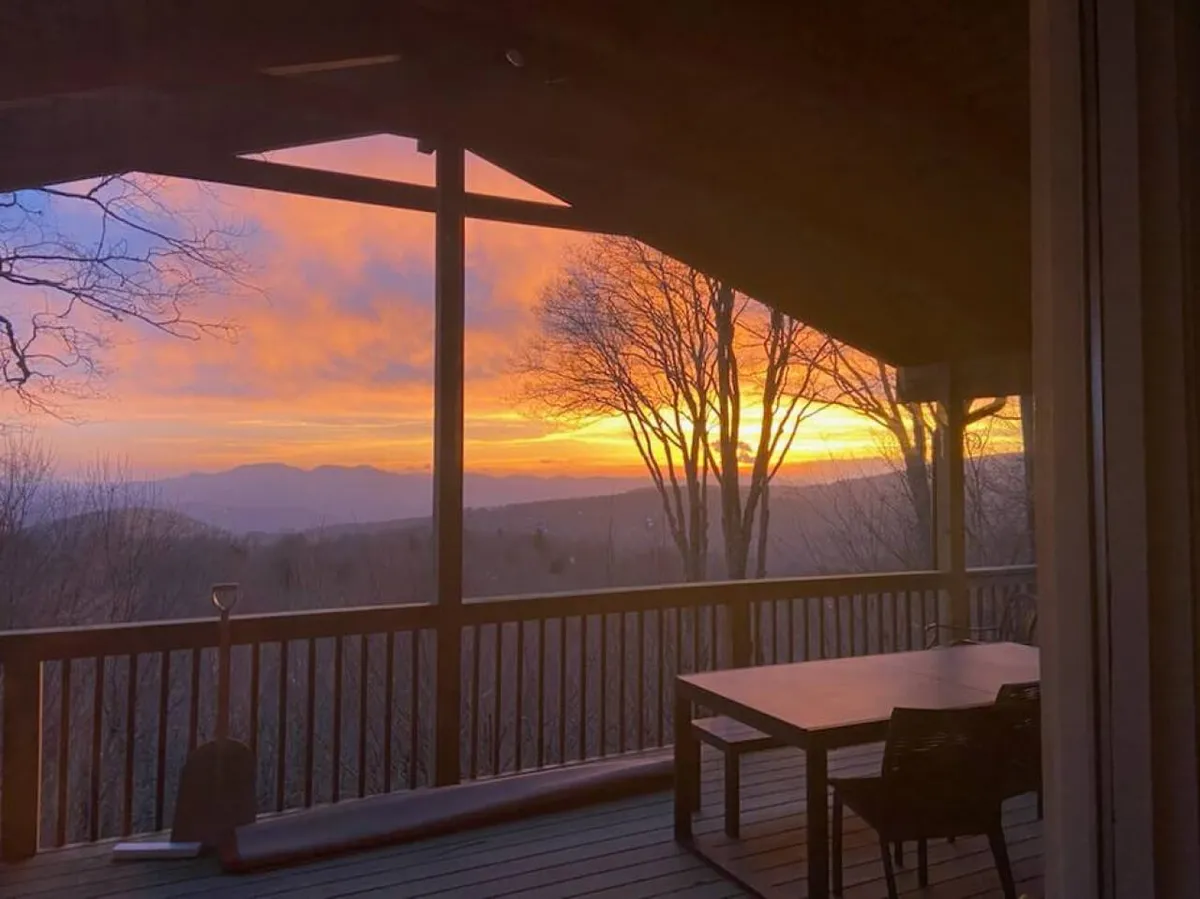 Captured at sunset, this view image showcases comfortable outdoor seating overlooking a spectacular mountain landscape. The tranquil setting is perfect for watching sunsets, gathering with friends, or stargazing under the open sky. The mood is peaceful, emphasizing the natural beauty surrounding the property.